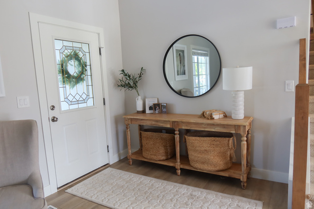 1204 North 3020th Street West Provo, UT 84601 - Photo 9 of 35 Entryway featuring a decorative glass paneled front door, light wood-finish flooring, a console table with turned legs, and a black-framed circular mirror