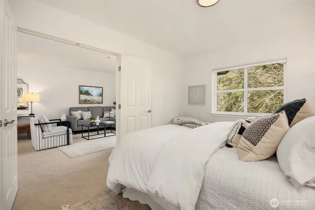 a bedroom with a bed couch and large windows