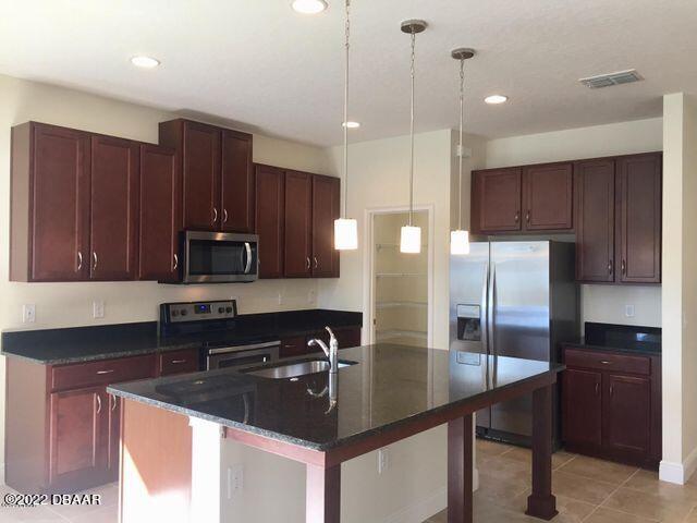 5435 Estero Loop Port Orange, FL 32128 - Photo 8 of 17 a kitchen with stainless steel appliances a sink a stove a refrigerator and cabinets