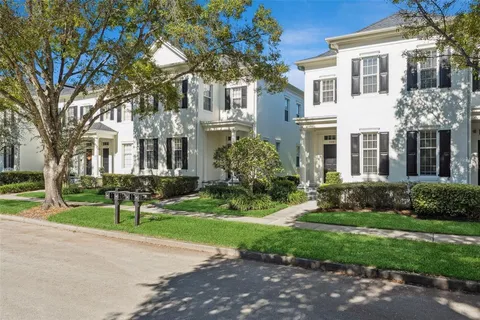 a view of a brick house with a yard and large trees