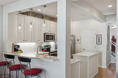 a kitchen with stainless steel appliances white cabinets and wooden floor