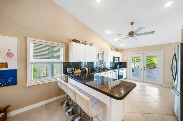 a kitchen with granite countertop a refrigerator a stove a sink a dining table and chairs with wooden floor