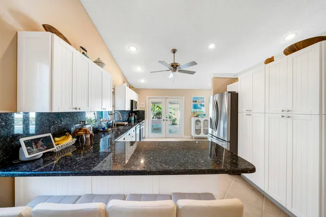 a kitchen with stainless steel appliances granite countertop a refrigerator a stove and white cabinets with wooden floor