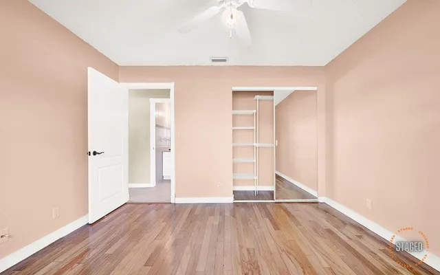 an empty room with wooden floor & closet and windows