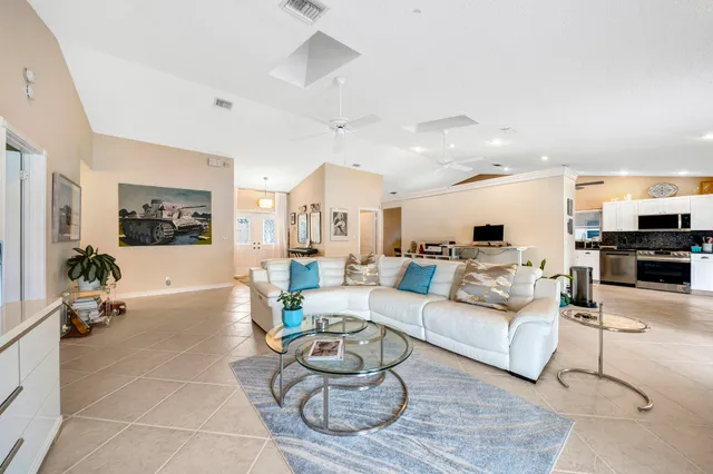 a living room with furniture kitchen view and a chandelier