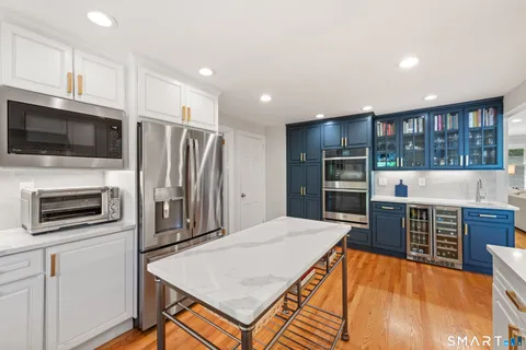 a kitchen with stainless steel appliances wooden floor and large window