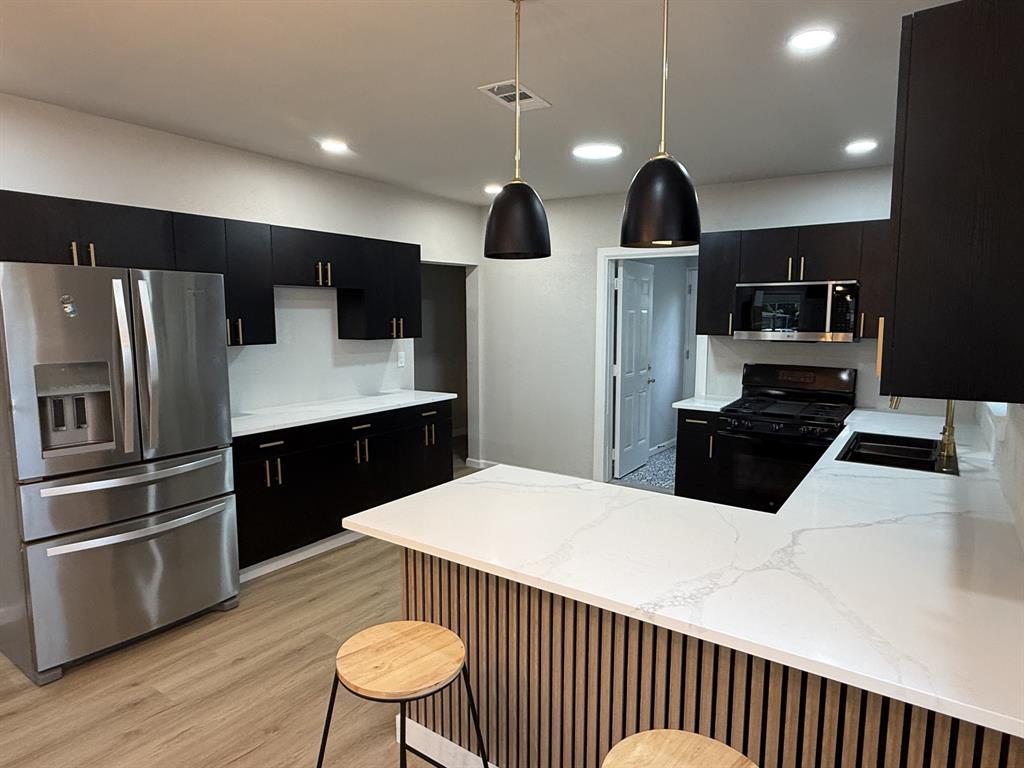 758 Bethpage Avenue Dallas, TX 75217 - Photo 4 of 20 a kitchen with stainless steel appliances kitchen island a sink a refrigerator and chairs