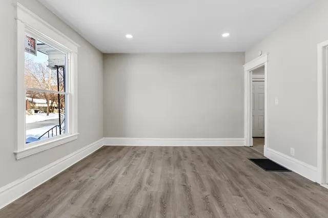 a view of an empty room with wooden floor and a window
