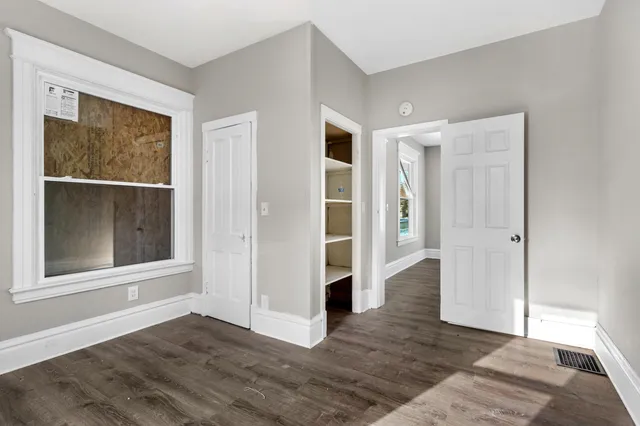 a view of an empty room with wooden floor and a window