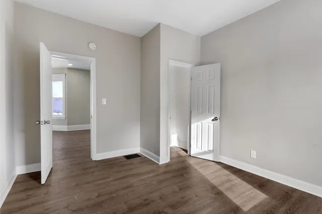 an empty room with wooden floor & windows