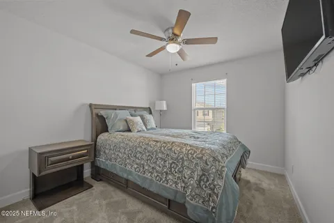 a bedroom with a bed next to a window with a chandelier