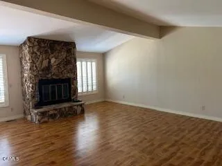 an empty room with wooden floor fireplace and windows