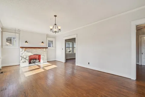 an empty room with wooden floor fireplace and windows