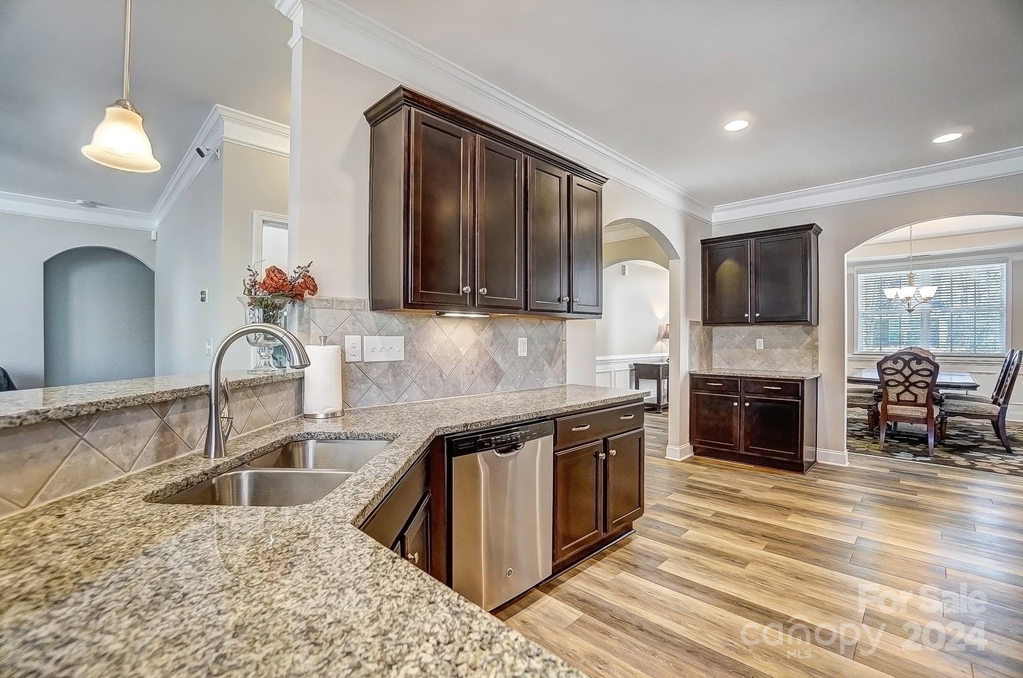 156 Annatto Way Tega Cay, SC 29708 - Photo 14 of 48 a kitchen with granite countertop a stove a sink and a dining table with wooden floor