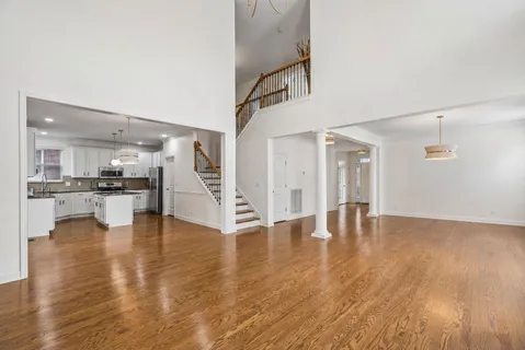 a view of empty room with wooden floor and kitchen view