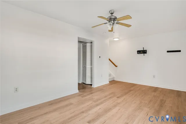 an empty room with wooden floor and ceiling fan
