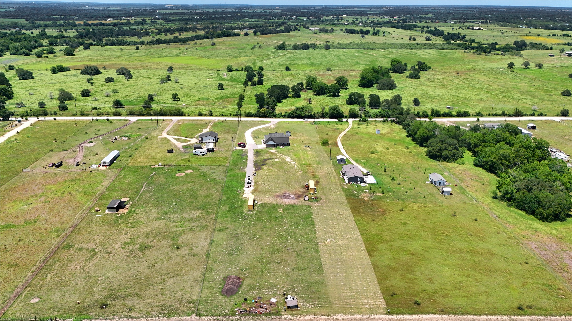 2889 Old McMahan Road Lockhart, TX 78644 - Photo 32 of 33 Spacious rural properties with multiple structures are visible amidst lush green landscapes.