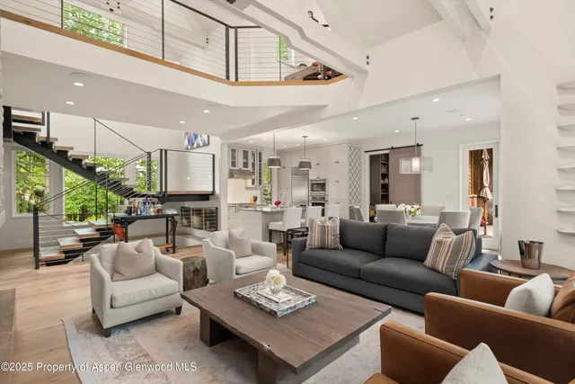 a living room with furniture kitchen view and a chandelier