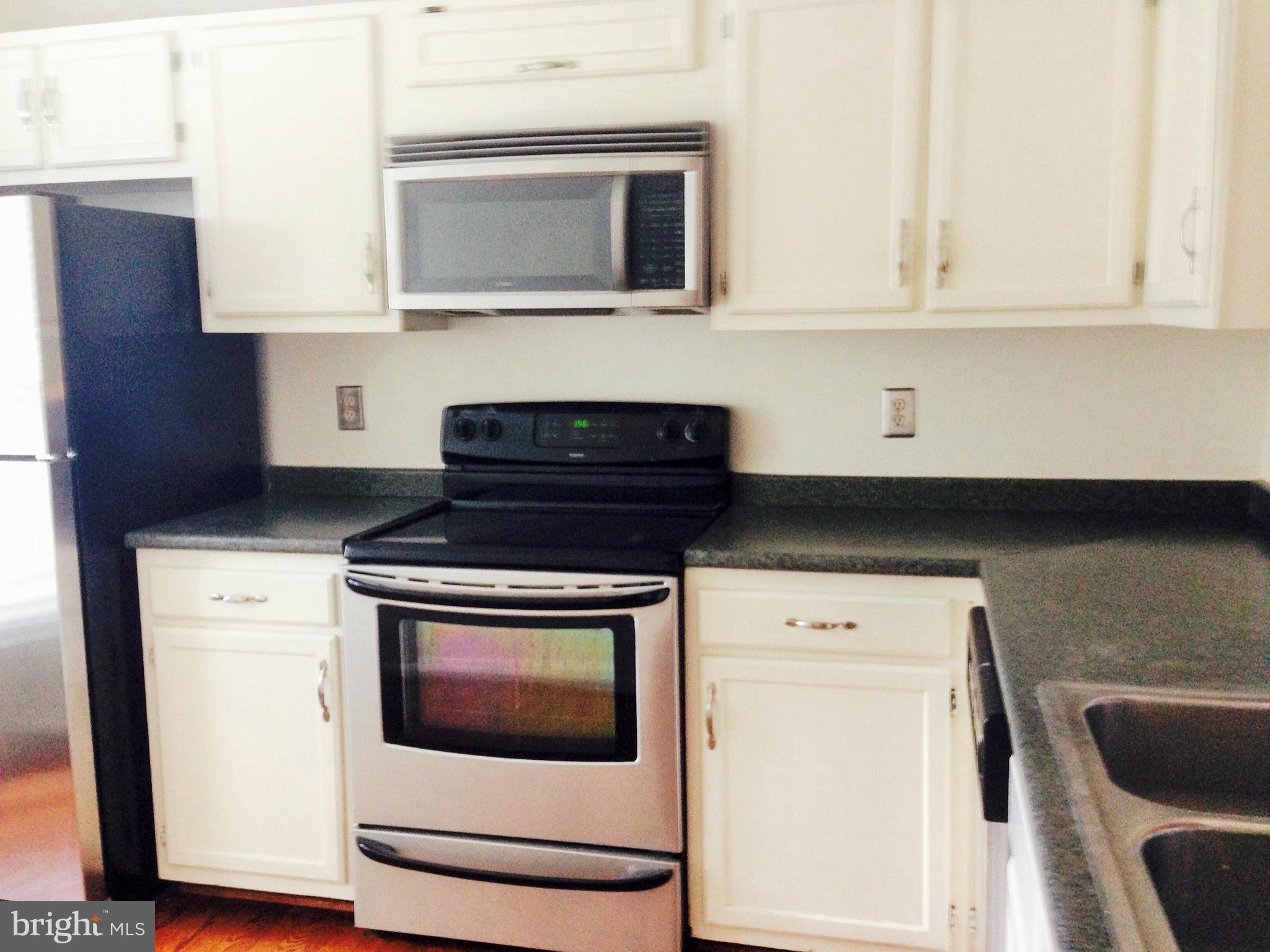 7933 Pebble Brook Court Springfield, VA 22153 - Photo 3 of 18 a kitchen with granite countertop white cabinets and black appliances