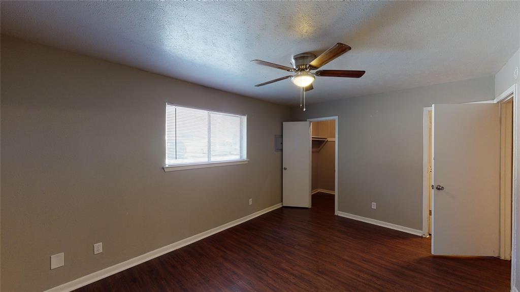 1407 15th Place, Unit A1AHR Plano, TX 75074 - Photo 11 of 14 Unfurnished bedroom featuring wood finished floors, a ceiling fan, and a spacious closet