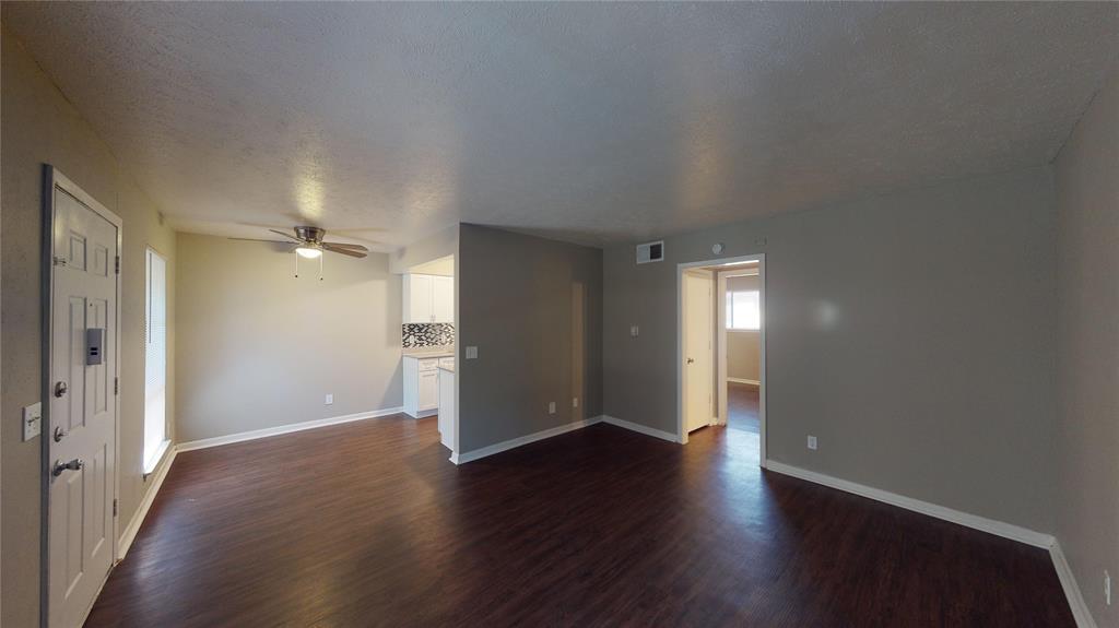 1407 15th Place, Unit A1AHR Plano, TX 75074 - Photo 2 of 14 Unfurnished living room featuring dark wood finished floors and a ceiling fan