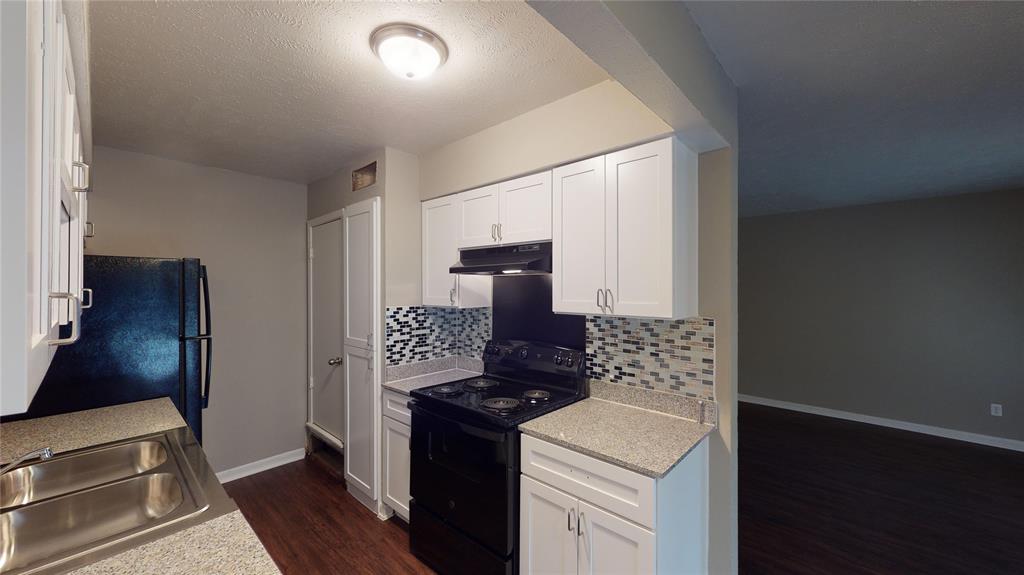 1407 15th Place, Unit A1AHR Plano, TX 75074 - Photo 7 of 14 Kitchen featuring black electric range, dark wood-style flooring, tasteful backsplash, and light countertops