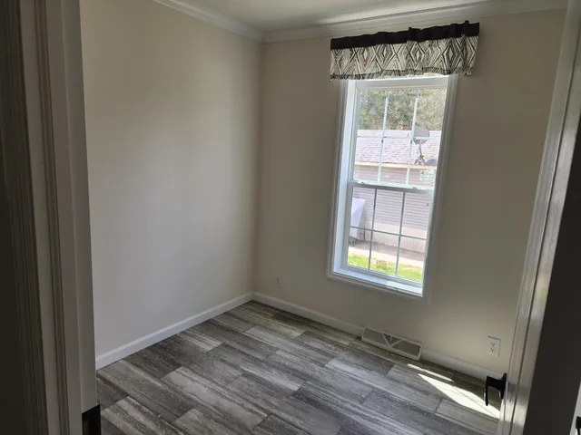 a view of empty room with wooden floor