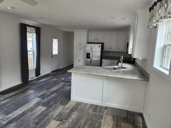 a kitchen with granite countertop a sink cabinets and wooden floor