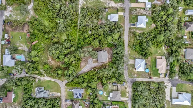 an aerial view of residential house with outdoor space and trees all around