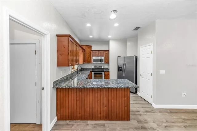 a kitchen with granite countertop wooden cabinets a sink and dishwasher