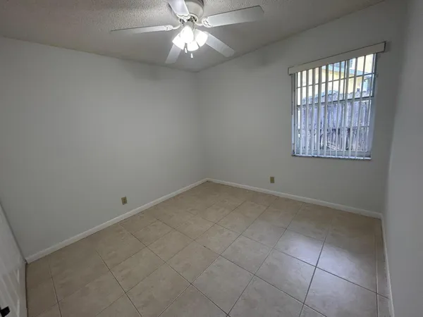 an empty room with a chandelier fan and windows