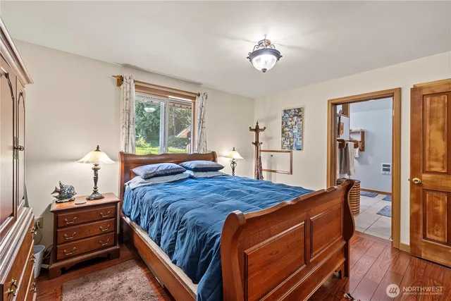 a bedroom with a bed and a dresser with wooden floor