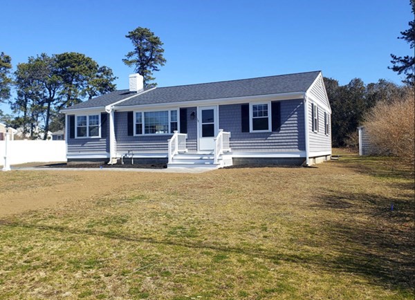 a front view of house with yard and trees in the background