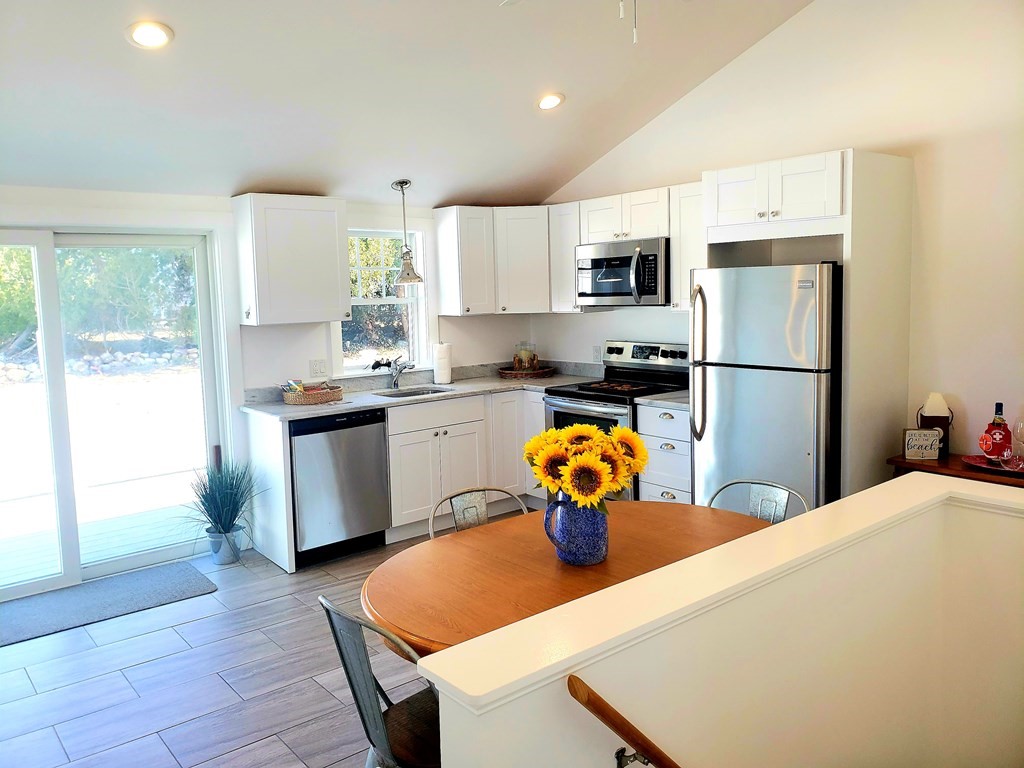 18 Harvard Road Dennis, MA 02639 - Photo 7 of 32 a kitchen with stainless steel appliances a refrigerator a sink a stove a dining table and chairs