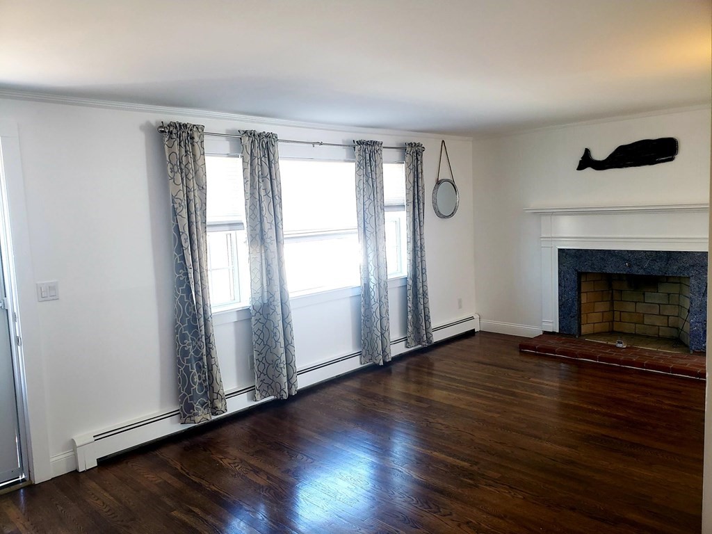 18 Harvard Road Dennis, MA 02639 - Photo 10 of 32 an empty room with wooden floor fireplace and windows