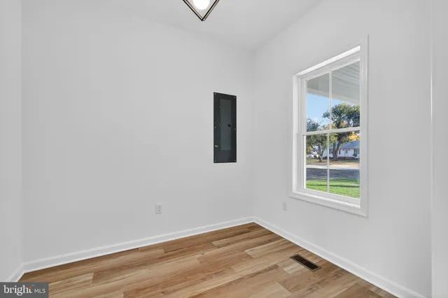 an empty room with wooden floor and windows