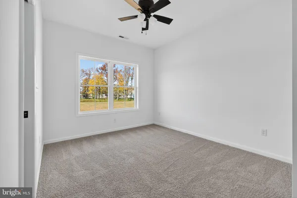 an empty room with windows and ceiling fan
