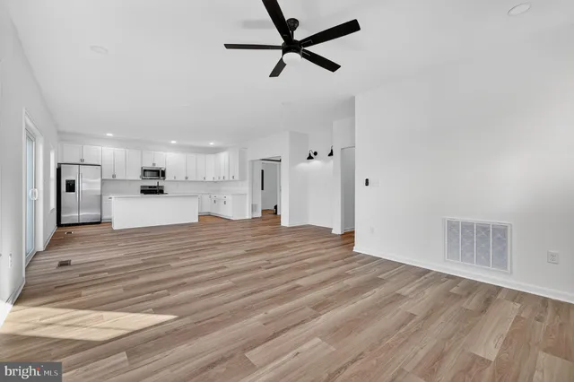 a view of a kitchen with a wooden floor and a ceiling fan