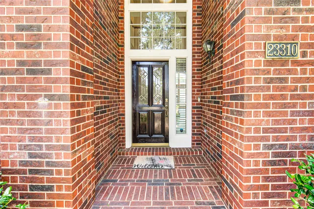 a front view of a house with garden and trees