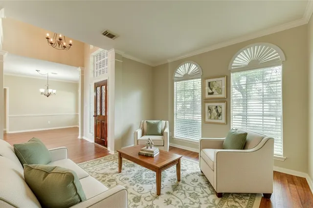 a view of a room with wooden floor chandelier and windows