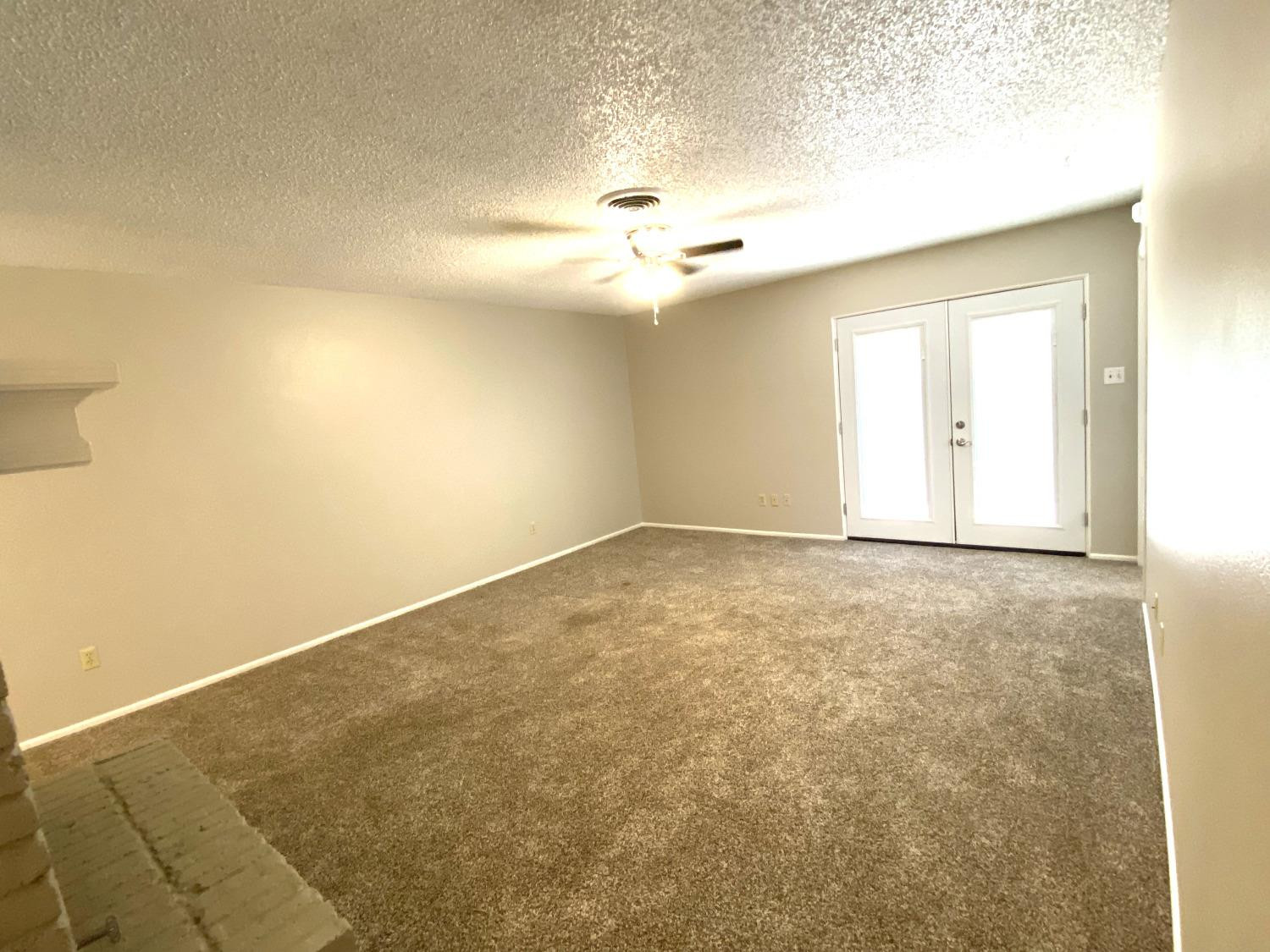 9818 Jordan Avenue, Unit A Lubbock, TX 79423 - Photo 15 of 20 an empty room with a ceiling fan and carpet