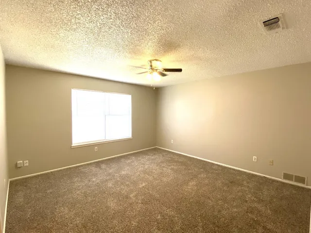 an empty room with windows and fan