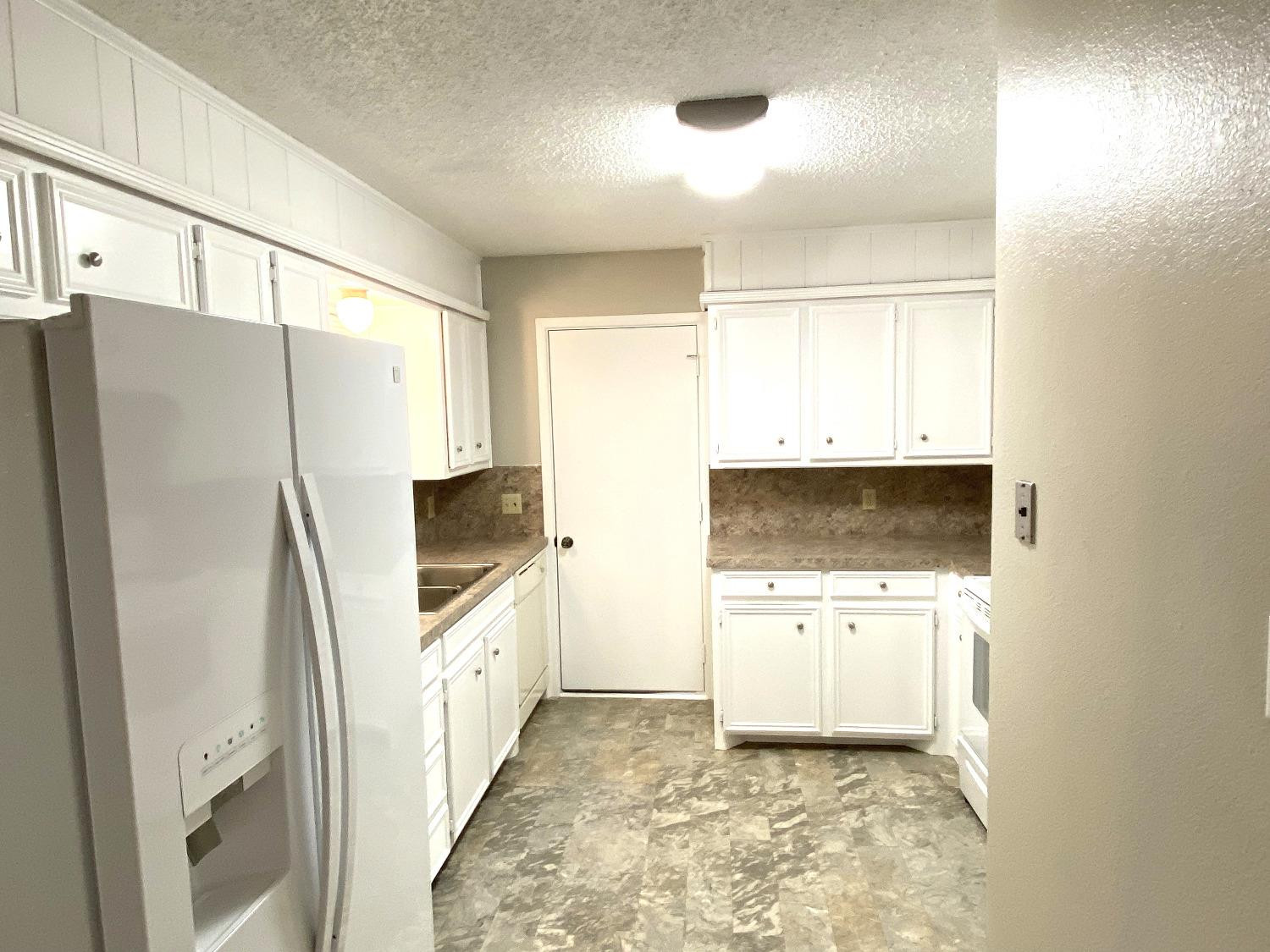 9818 Jordan Avenue, Unit A Lubbock, TX 79423 - Photo 3 of 20 a kitchen with a refrigerator a stove top oven and a sink