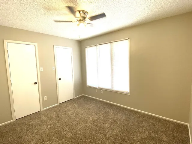 an empty room with a ceiling fan and a window
