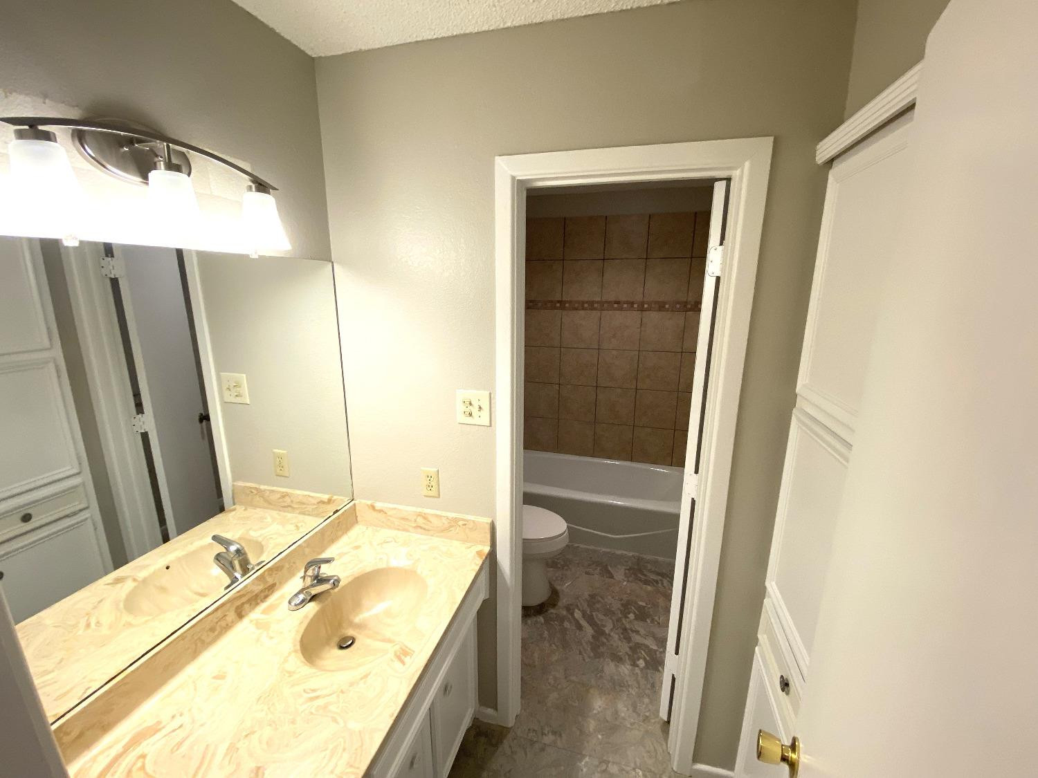 9818 Jordan Avenue, Unit A Lubbock, TX 79423 - Photo 10 of 20 a bathroom with a granite countertop sink and a mirror