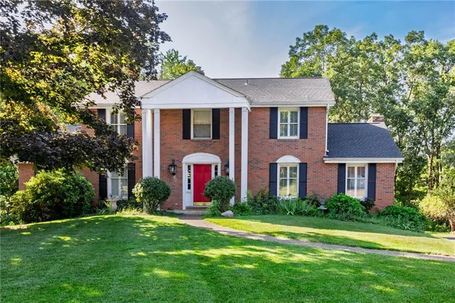 a front view of a house with a yard and trees