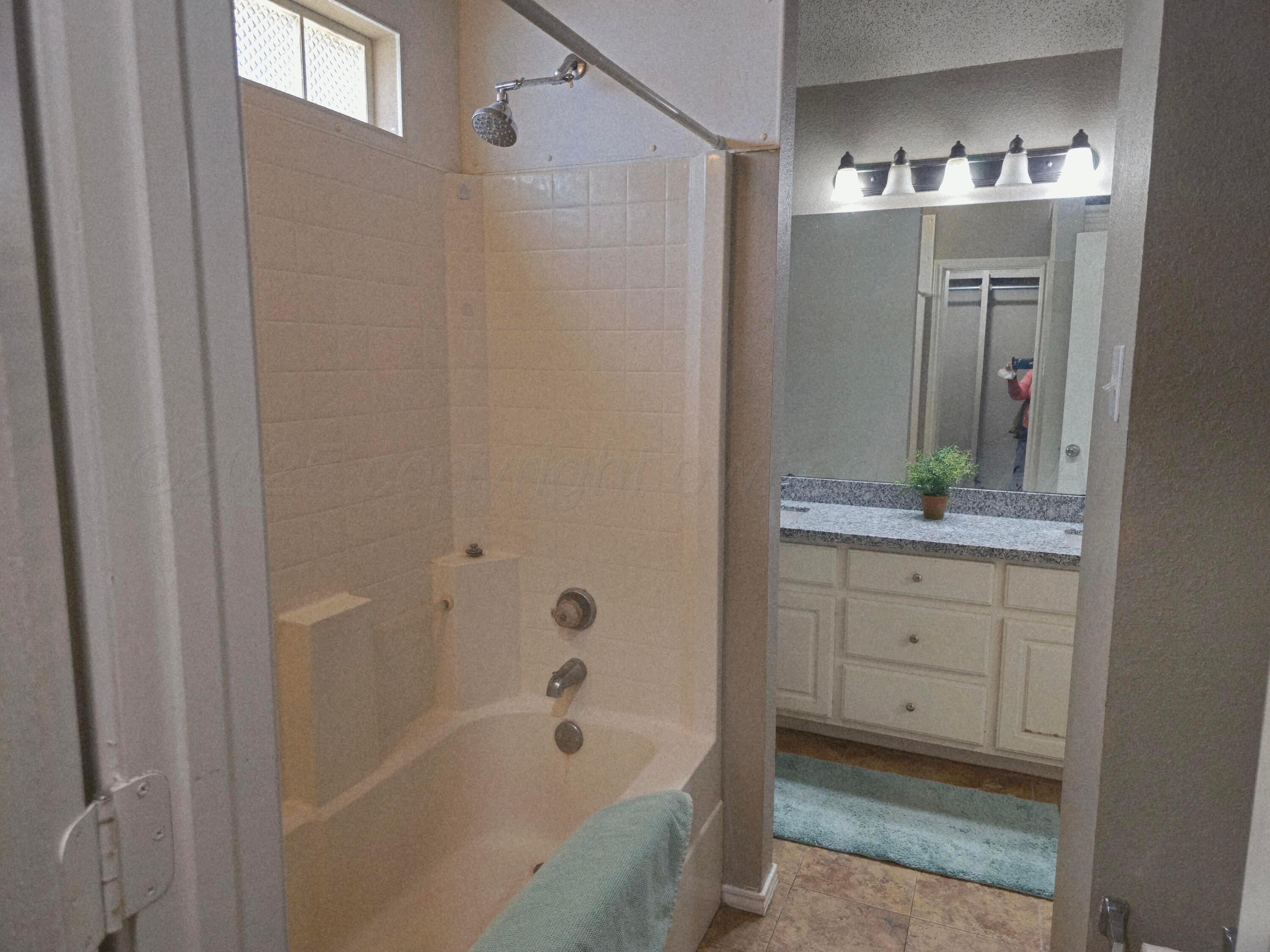 1918 75th Street Lubbock, TX 79423 - Photo 13 of 23 a bathroom with a bathtub sink vanity and mirror