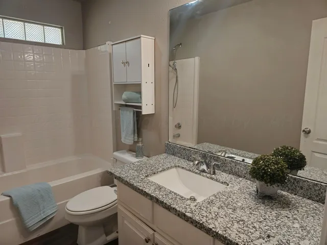 a bathroom with a granite countertop sink toilet and shower