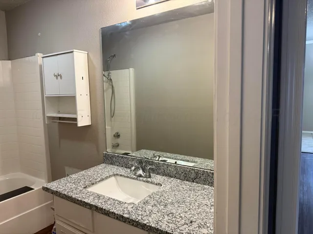 a bathroom with a granite countertop sink and a mirror
