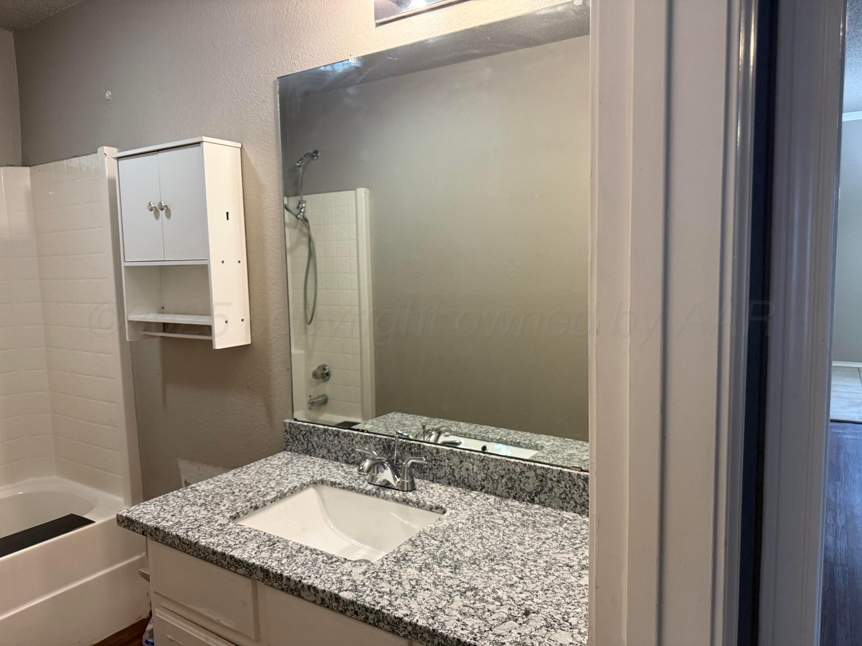 1918 75th Street Lubbock, TX 79423 - Photo 19 of 23 a bathroom with a granite countertop sink and a mirror